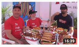 Crude Brothers at Pink's Hot Dogs at table with a lot of different types of hot dogs