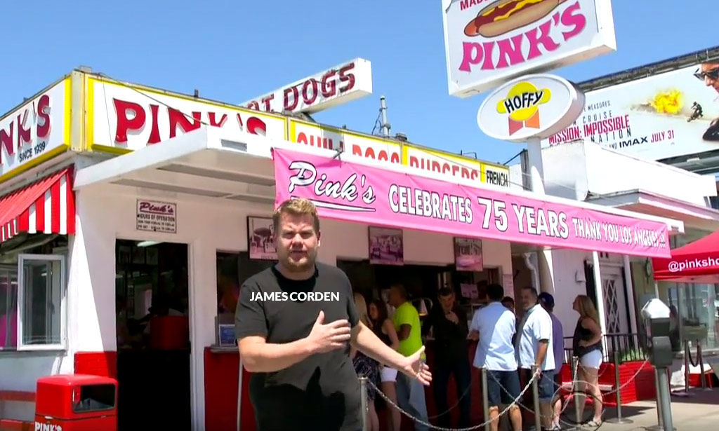 James Corden standing in front of Pink's Hot Dog stand in Hollywood California