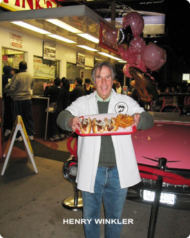 Photo of Henry Winkler holding a plate of hot dogs at Pink's Hot Dogs
