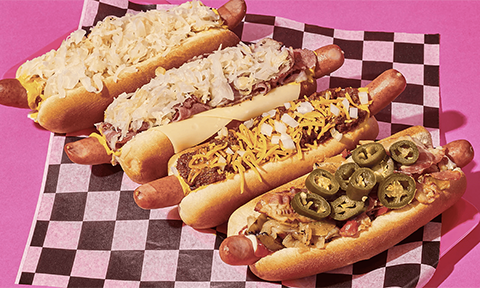 Four different style hot dogs with all kinds of toppings on them.