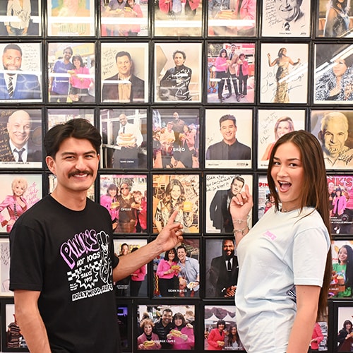 Two patrons admiring the enormous wall of movie stars that have visited Pink's.